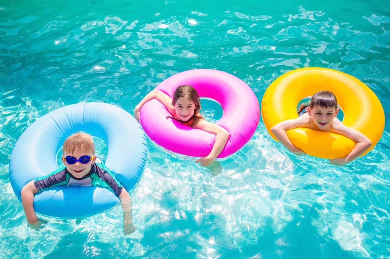 The Act Hotel Шарджа Екстер'єр фото Children using inner tubes in a swimming pool